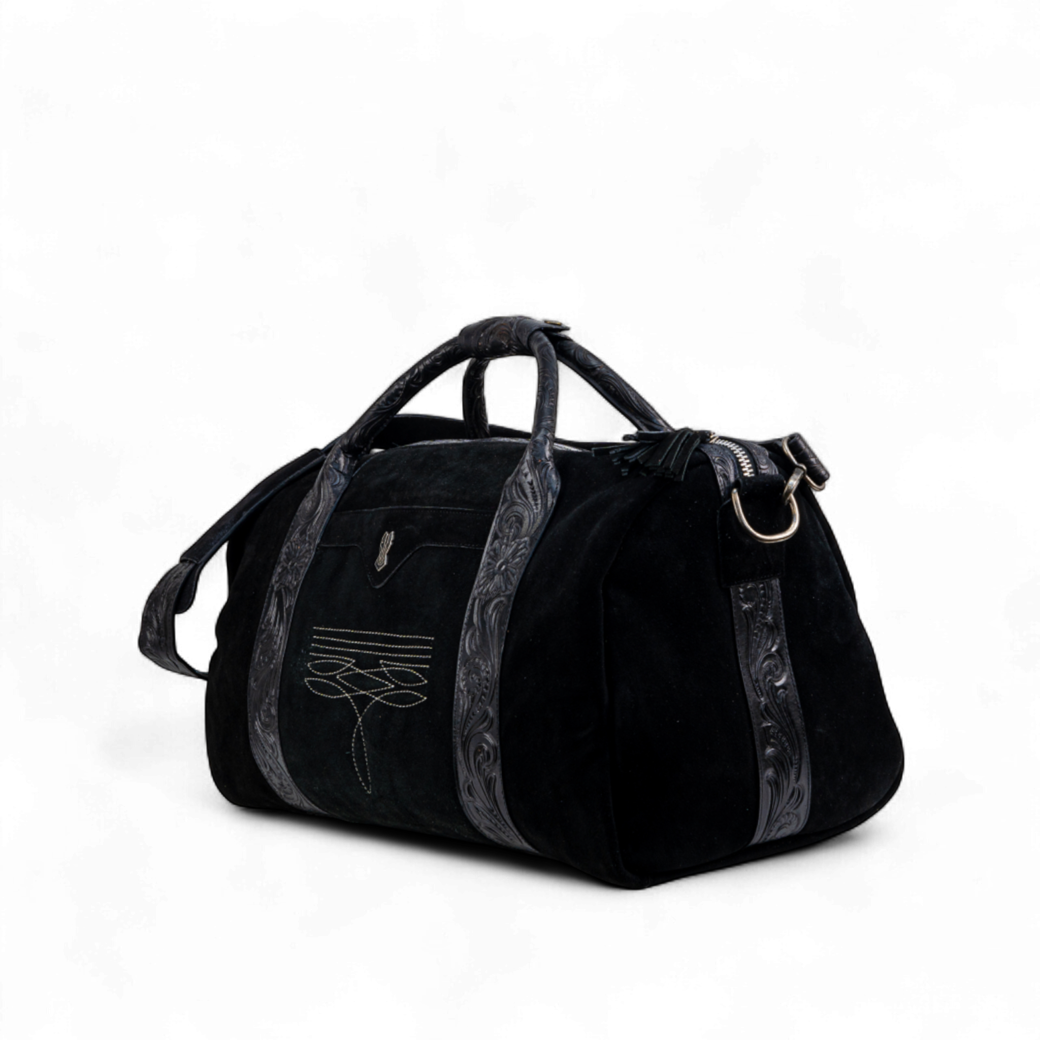 Black suede duffel bag with tooled leather trim and handles, featuring decorative stitching on the front pocket. The bag has a structured shape with metal D-rings and an adjustable shoulder strap
