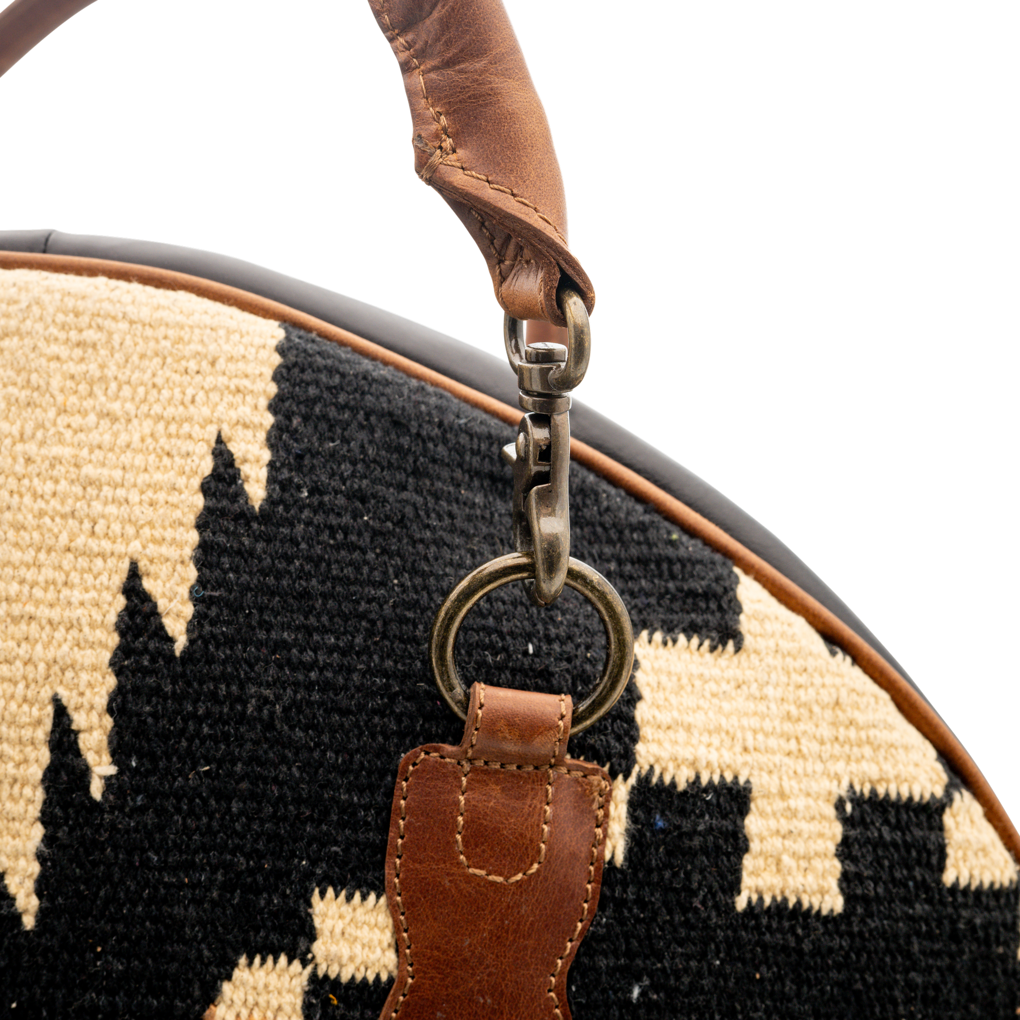 Close-up of a woven bag with a leather strap and clasp on a white background