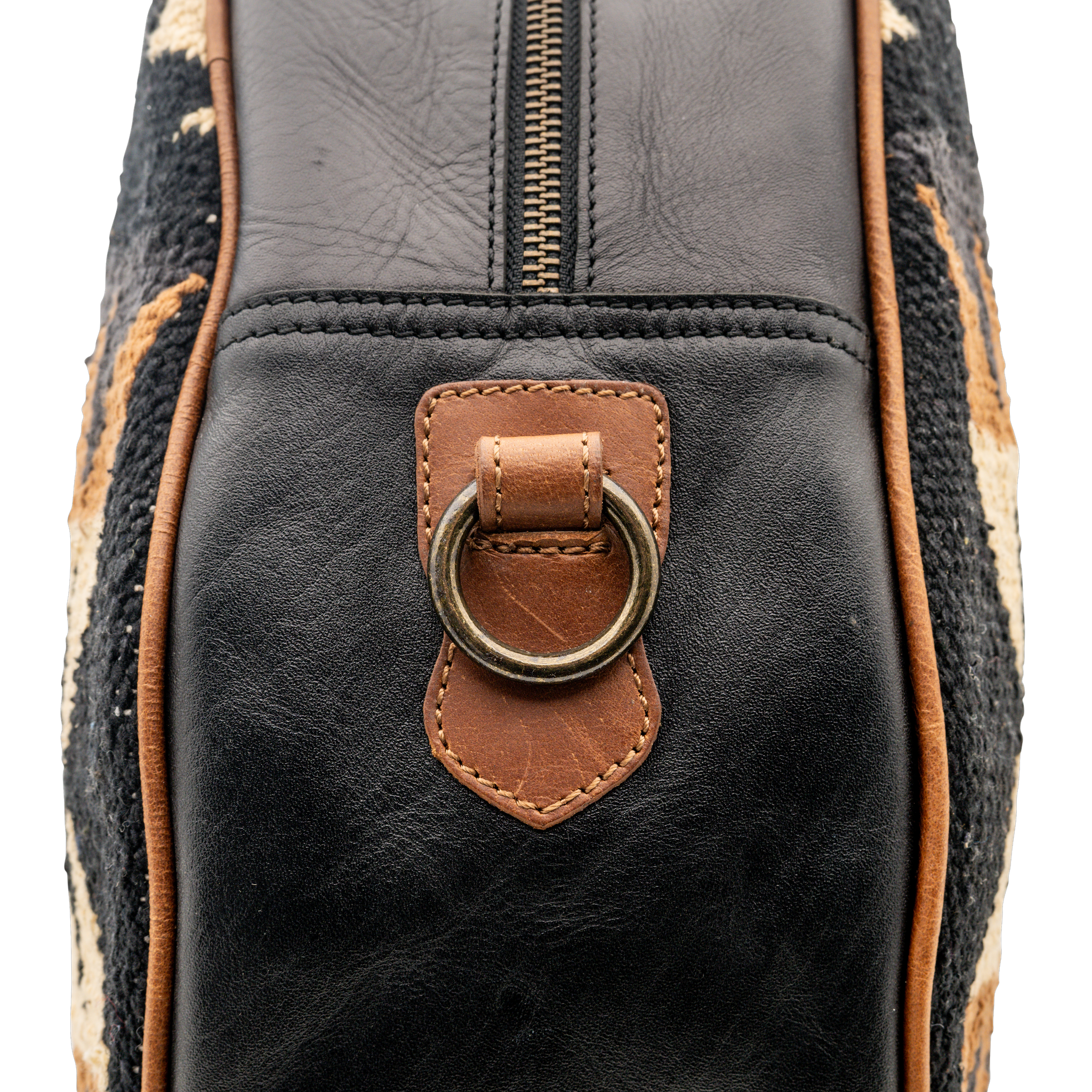 Close-up of a black leather bag with brown accents and a gold ring detail on a white background