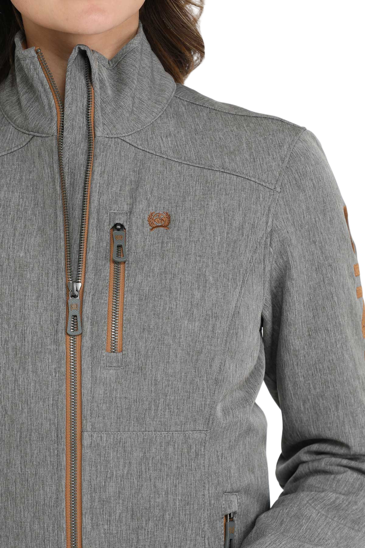 Close-up of a woman wearing a light gray softshell jacket with brown zipper accents 