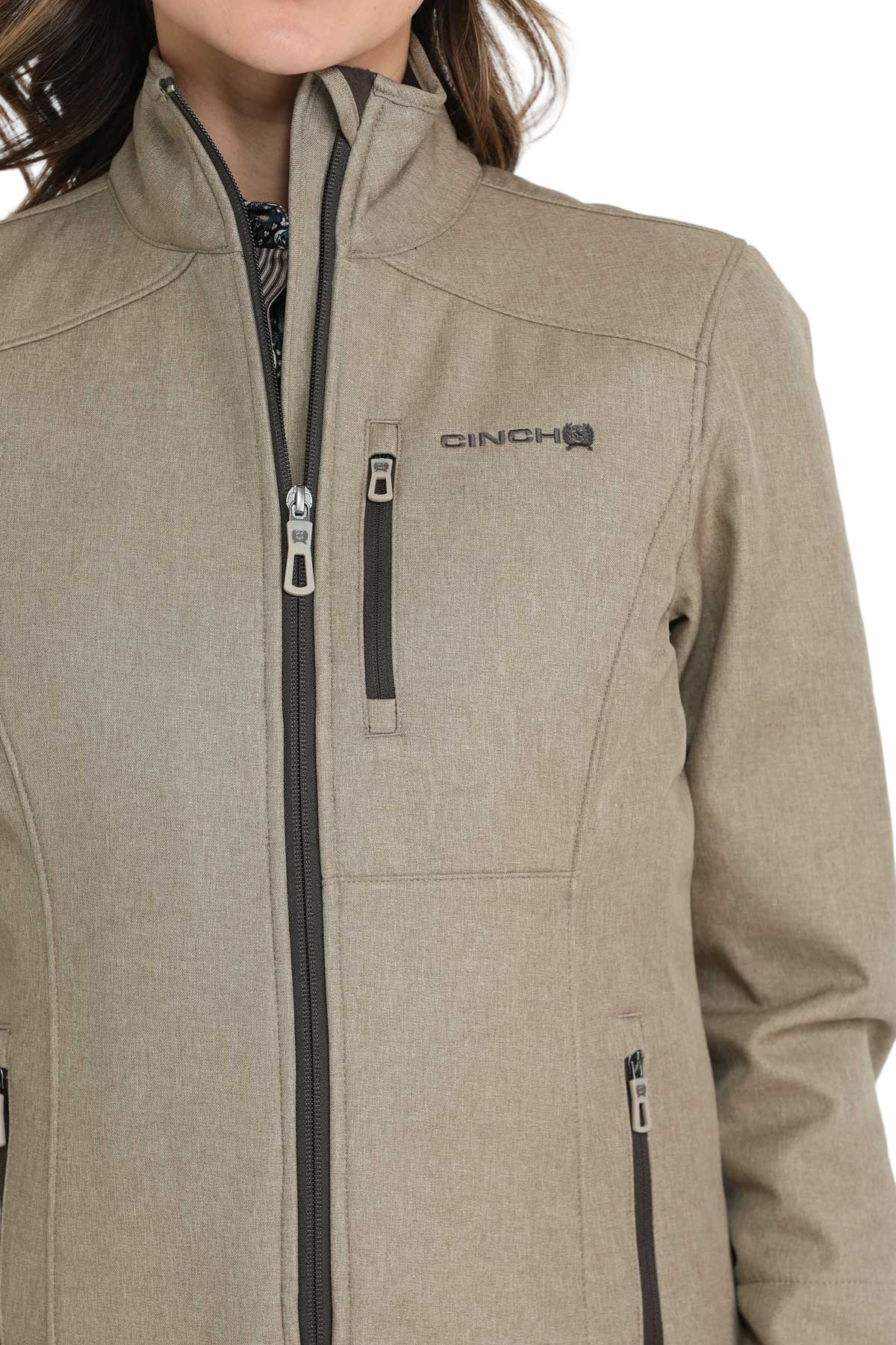 Close-up of a woman wearing a light olive zip-up jacket with a high collar and front pockets