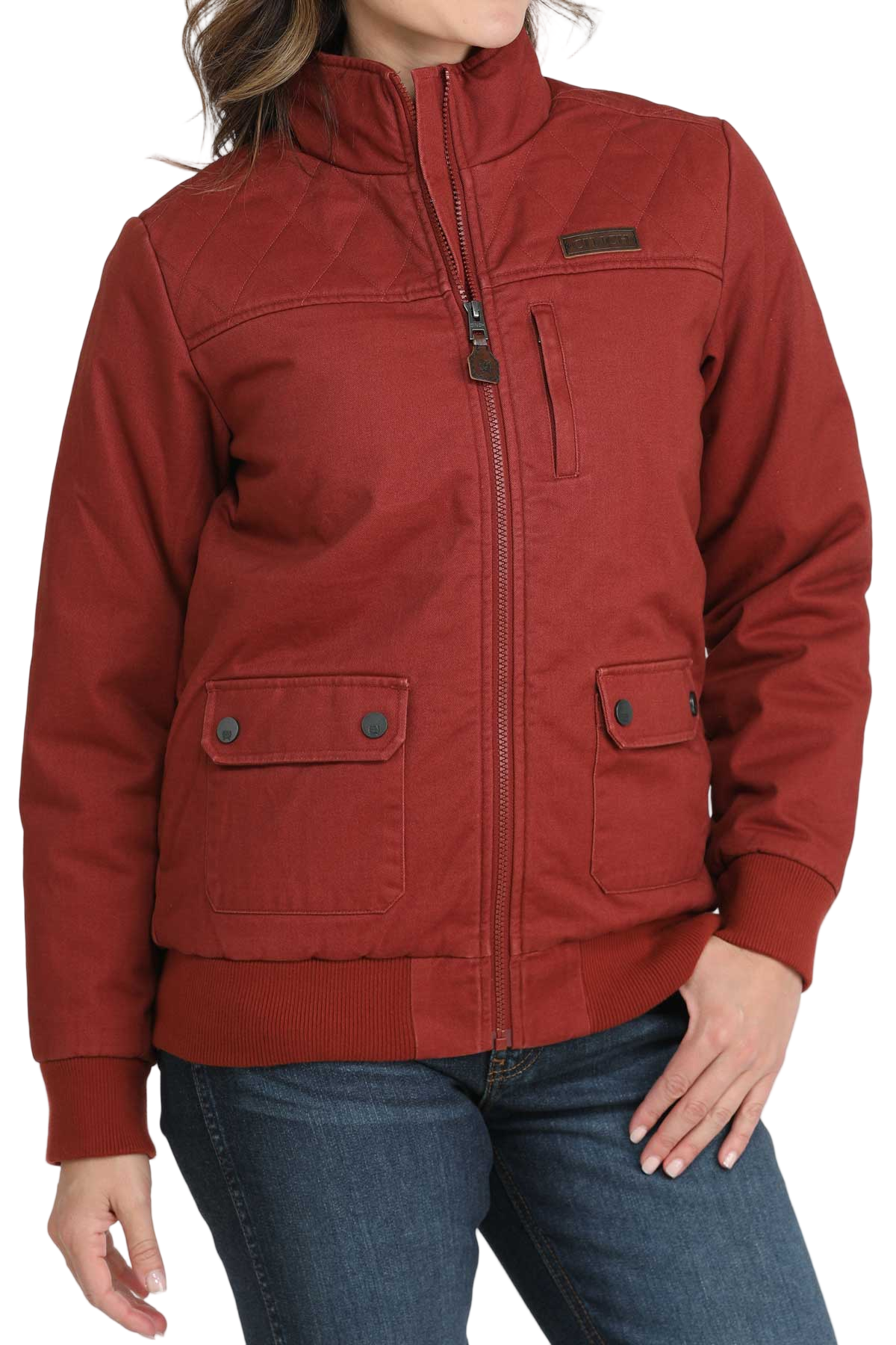 Woman wearing a red zip-up jacket with front flap pockets and dark jeans