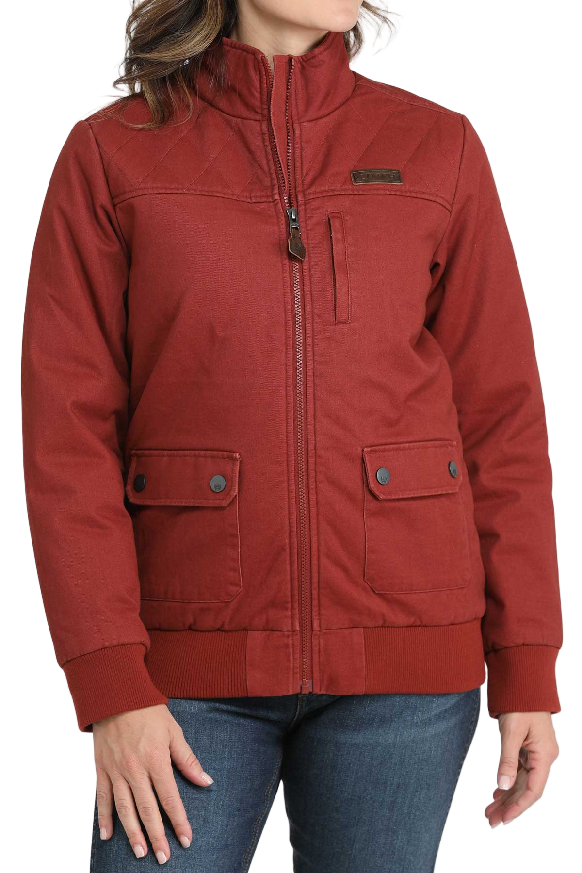 Woman wearing a red zip-up jacket with front flap pockets and dark jeans