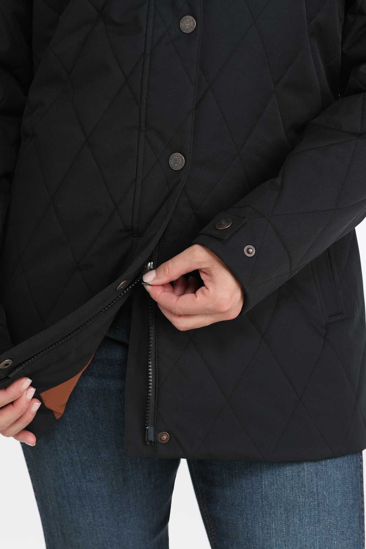 Close-up of a woman wearing a black coat with jeans specifically focusing on the zipper