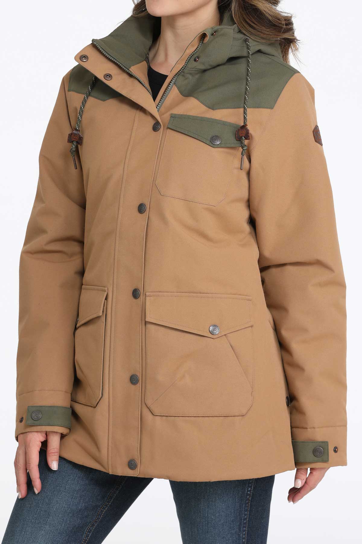 Woman wearing a brown jacket with green accents and jeans 