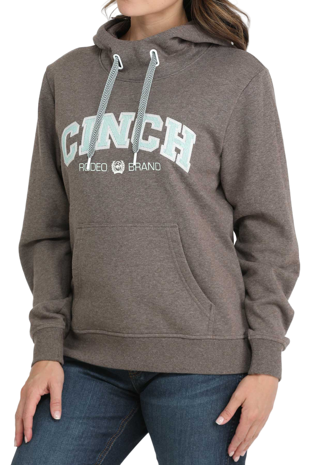 Woman wearing a brown CINCH hoodie with blue drawstrings and a front kangaroo pocket, paired with blue jeans