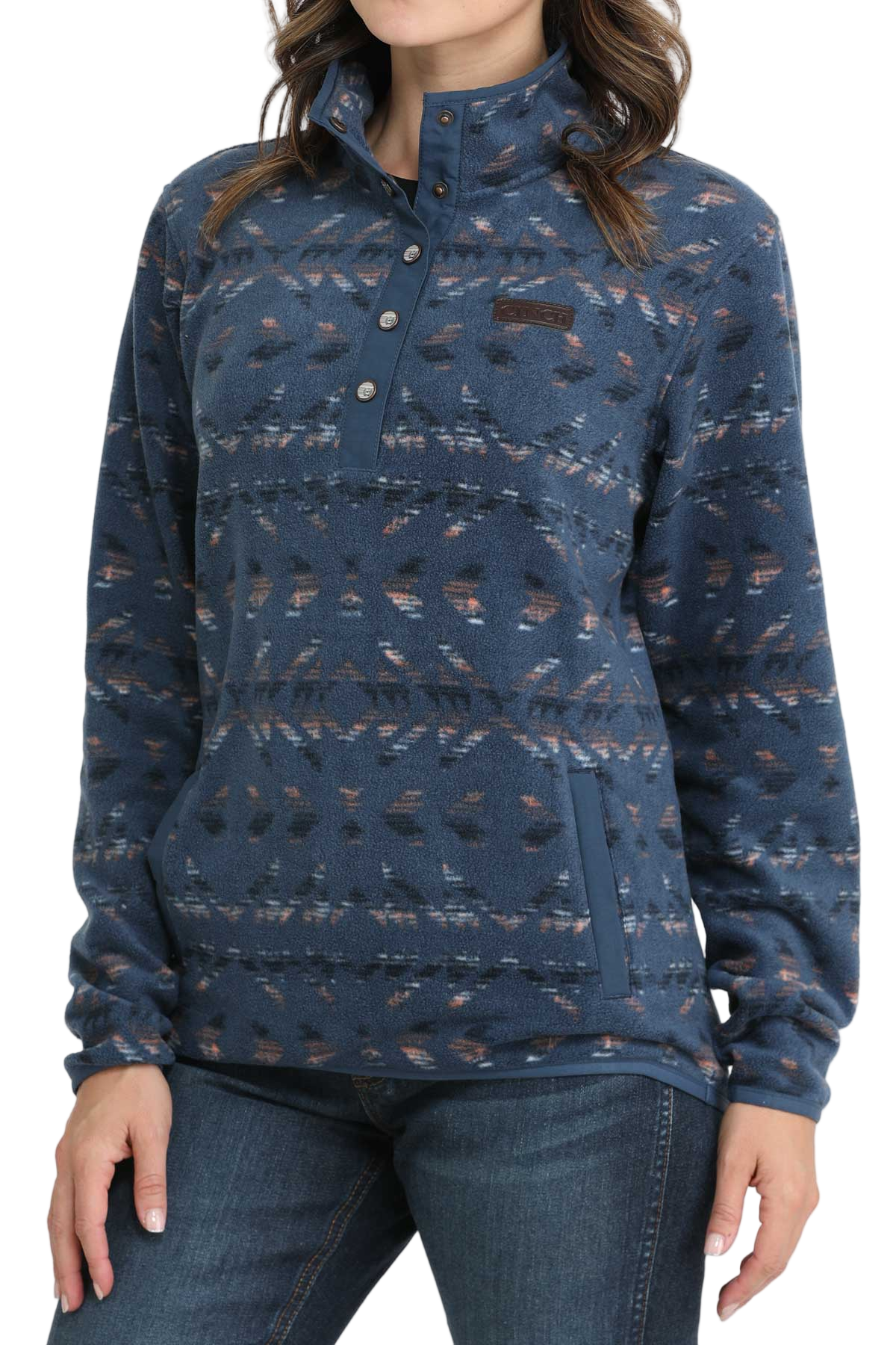 Woman wearing a blue patterned fleece pullover with a snap-up collar and front pocket, paired with dark denim jeans