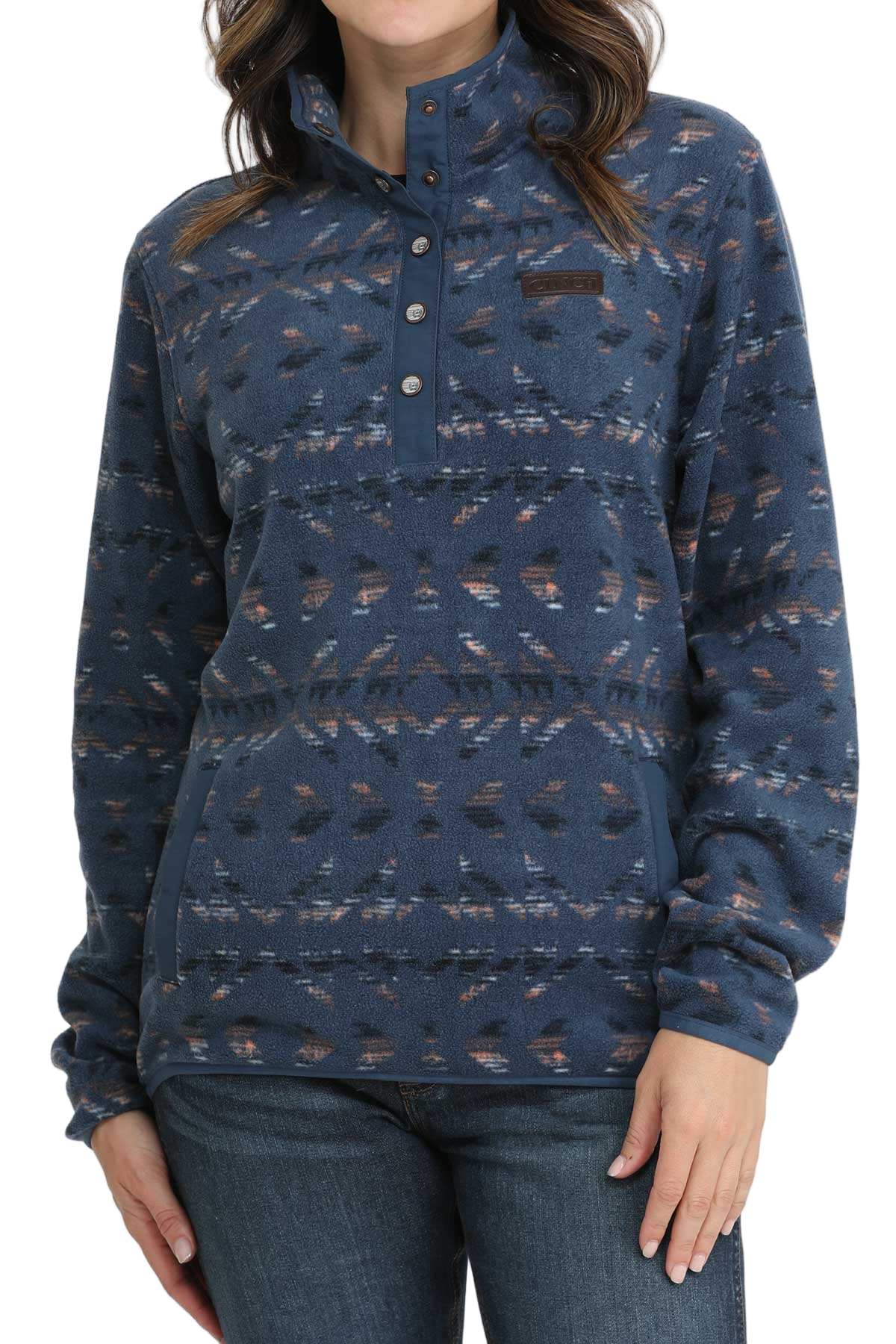 Woman wearing a blue patterned fleece pullover with a snap-up collar and front pocket, paired with dark denim jeans