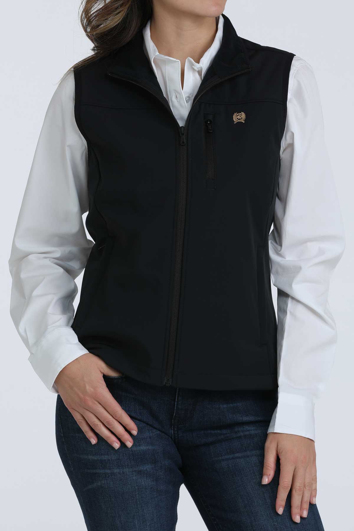 Woman wearing a black vest with a white undershirt and jeans 
