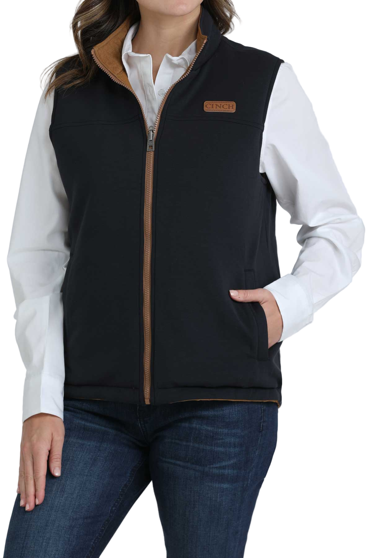 Woman wearing a black quilted vest over a white button-up shirt and dark jeans 