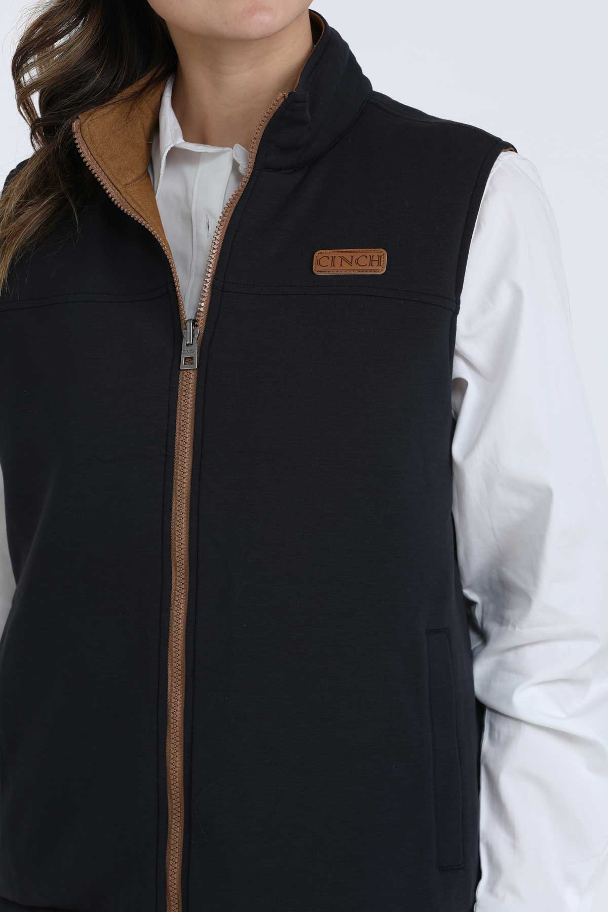 Close-up of a woman wearing a black vest with a white undershirt 