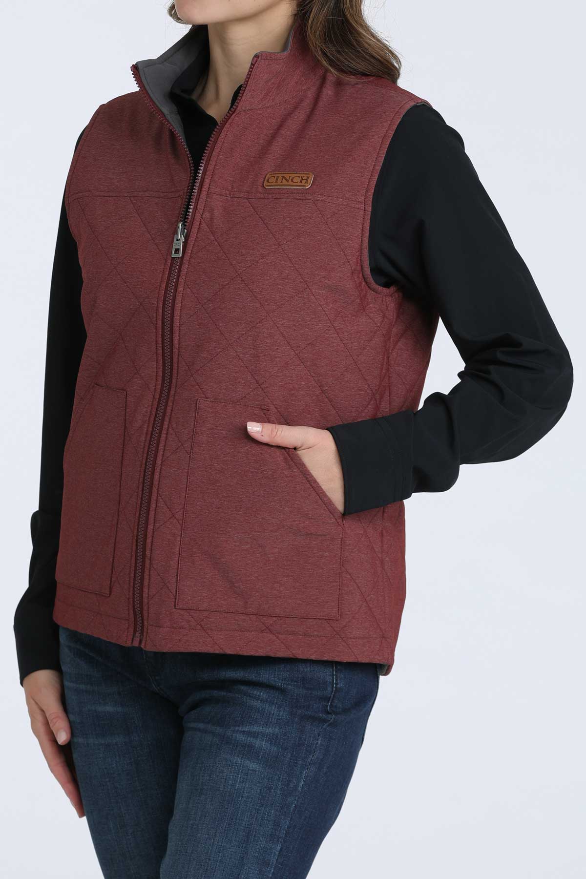 Woman wearing a burgundy vest with a black undershirt and jeans 