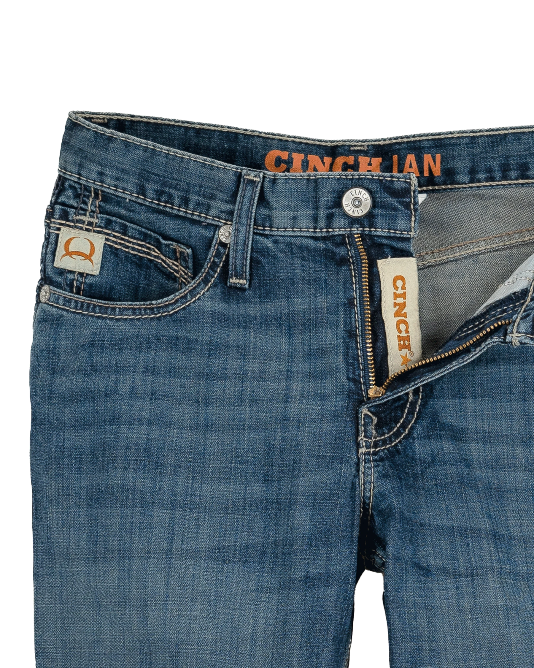 Close-up of blue jeans with Cinch brand labels on a white background