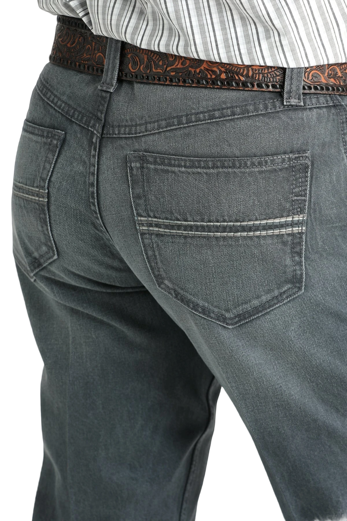Close-up of the back of a person wearing gray denim jeans with simple stitching on the back pockets and a tooled brown leather belt, paired with a tucked-in patterned shirt
