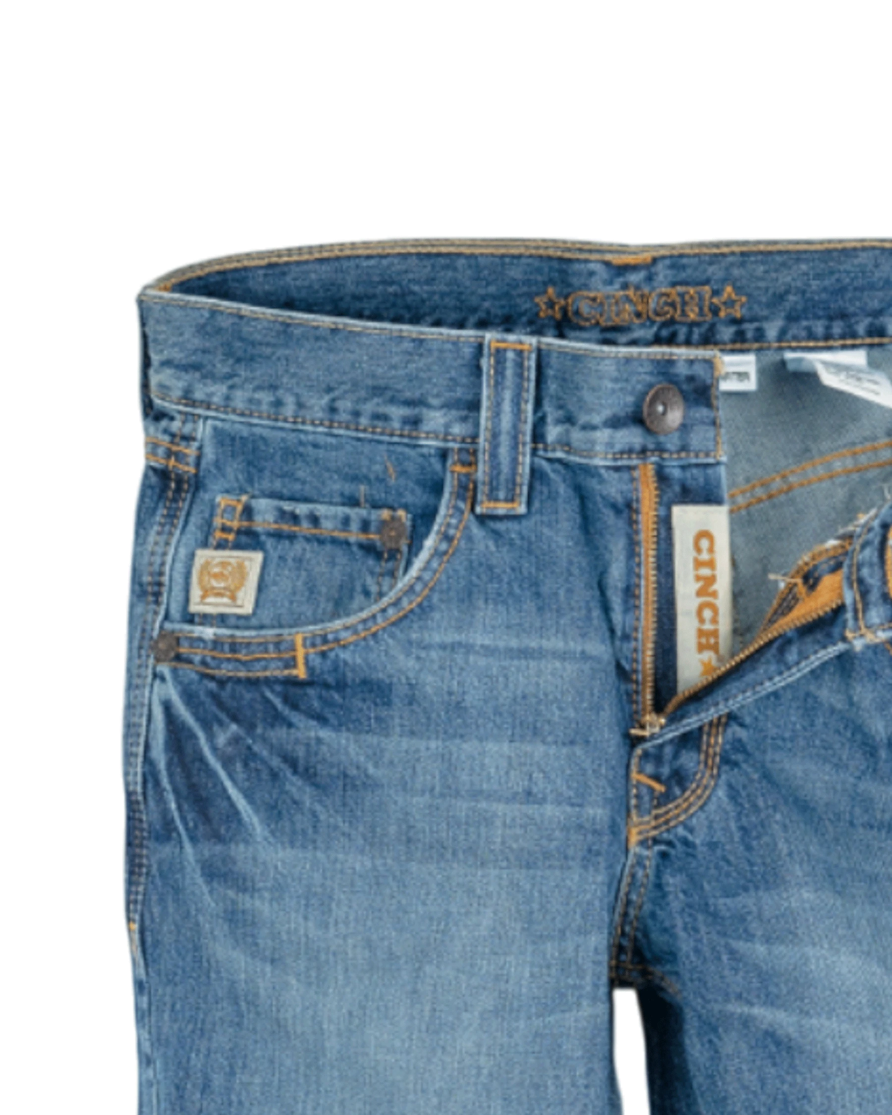 Close-up of the front of blue denim jeans with light fading, featuring a coin pocket with a small embroidered patch, belt loops, and a button closure with a zipper fly. The waistband has 'CINCH' stitched in gold thread