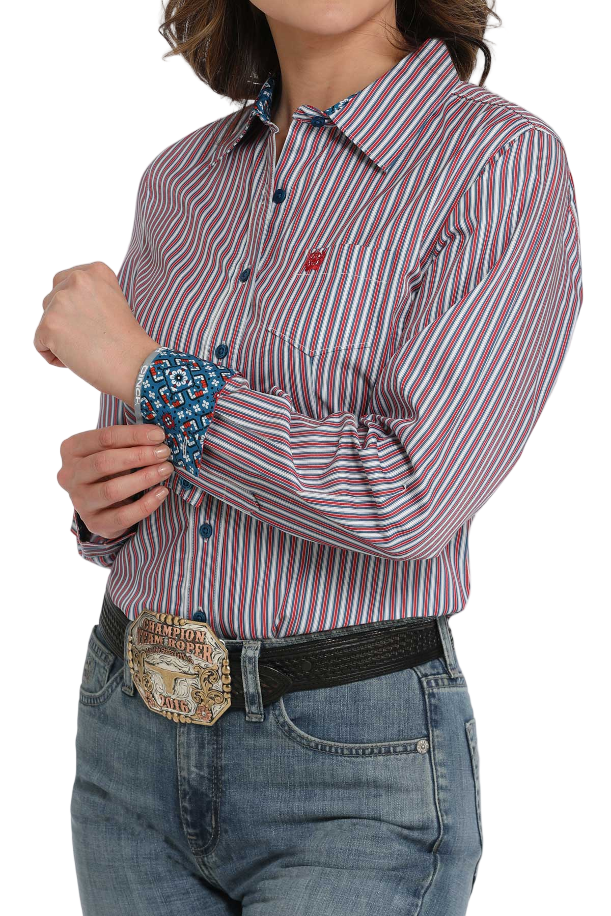 Woman wearing a purple striped long-sleeve button-down shirt with contrasting cuffs, paired with jeans and a large western belt buckle