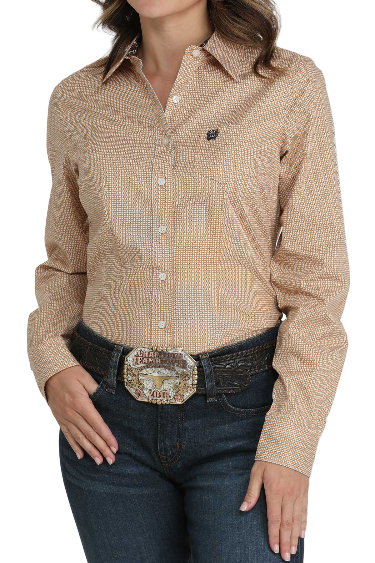 Woman wearing a tan patterned button-down shirt, paired with dark jeans and a large silver belt buckle