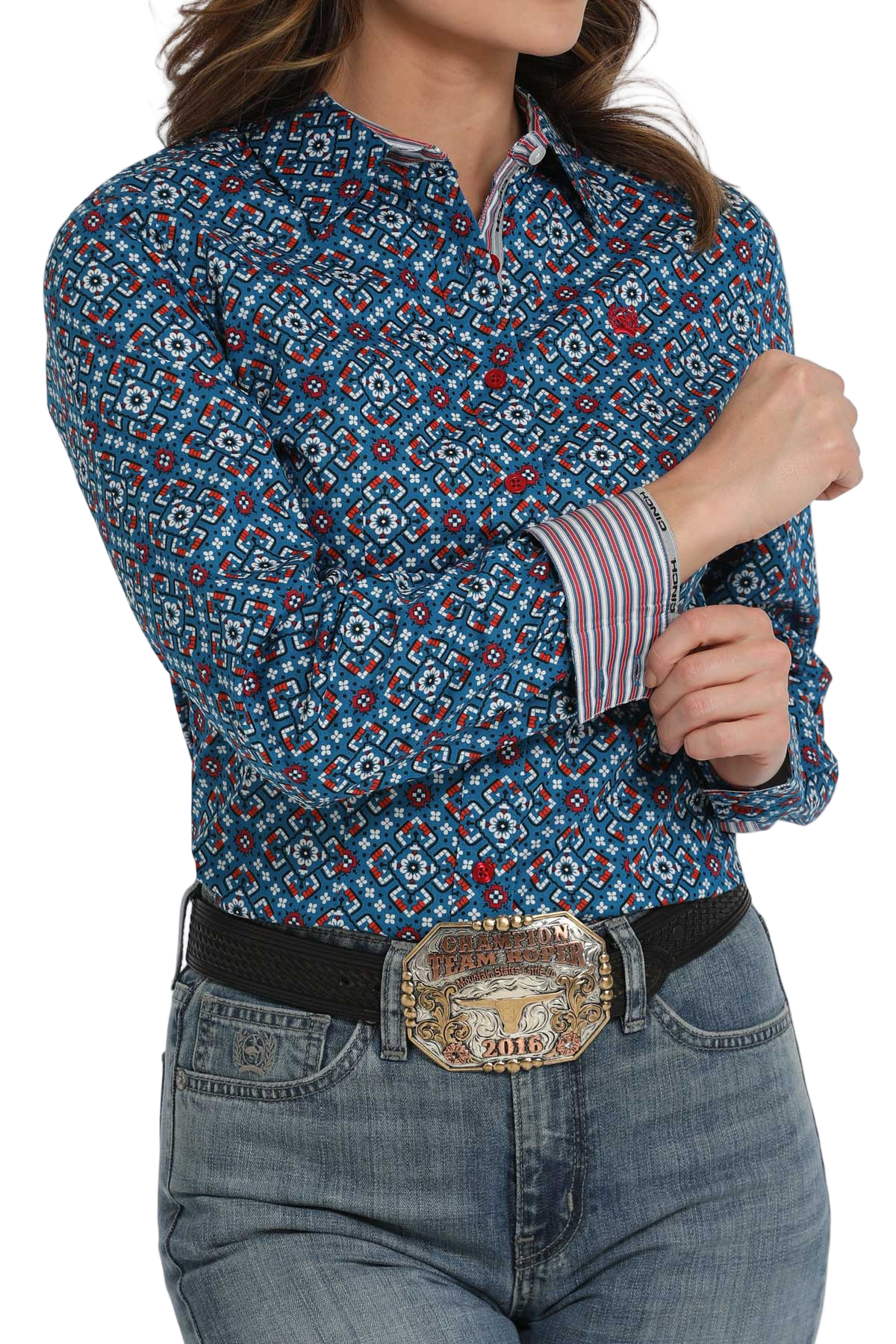 Woman wearing a blue patterned long-sleeve shirt with contrasting cuffs paired with light-wash jeans and a belt with a decorative buckle