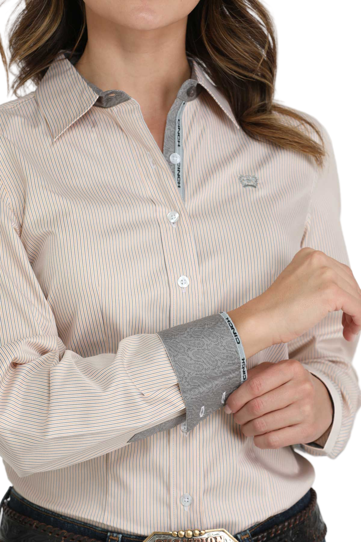 Close-up of a woman wearing a beige striped button-down shirt with patterned contrast cuffs