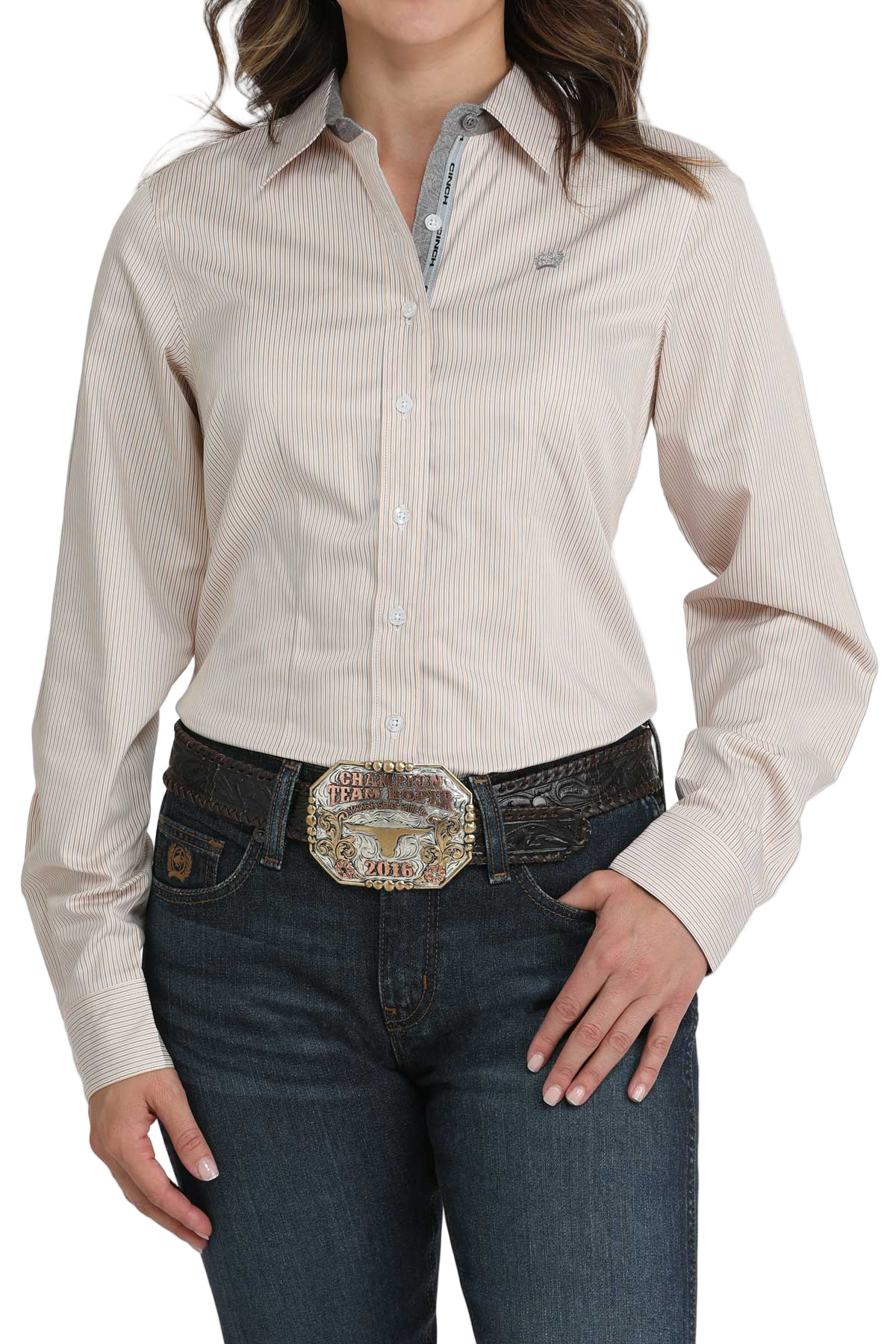 Woman wearing a beige striped button-down shirt, paired with dark blue jeans and a large silver western belt buckle