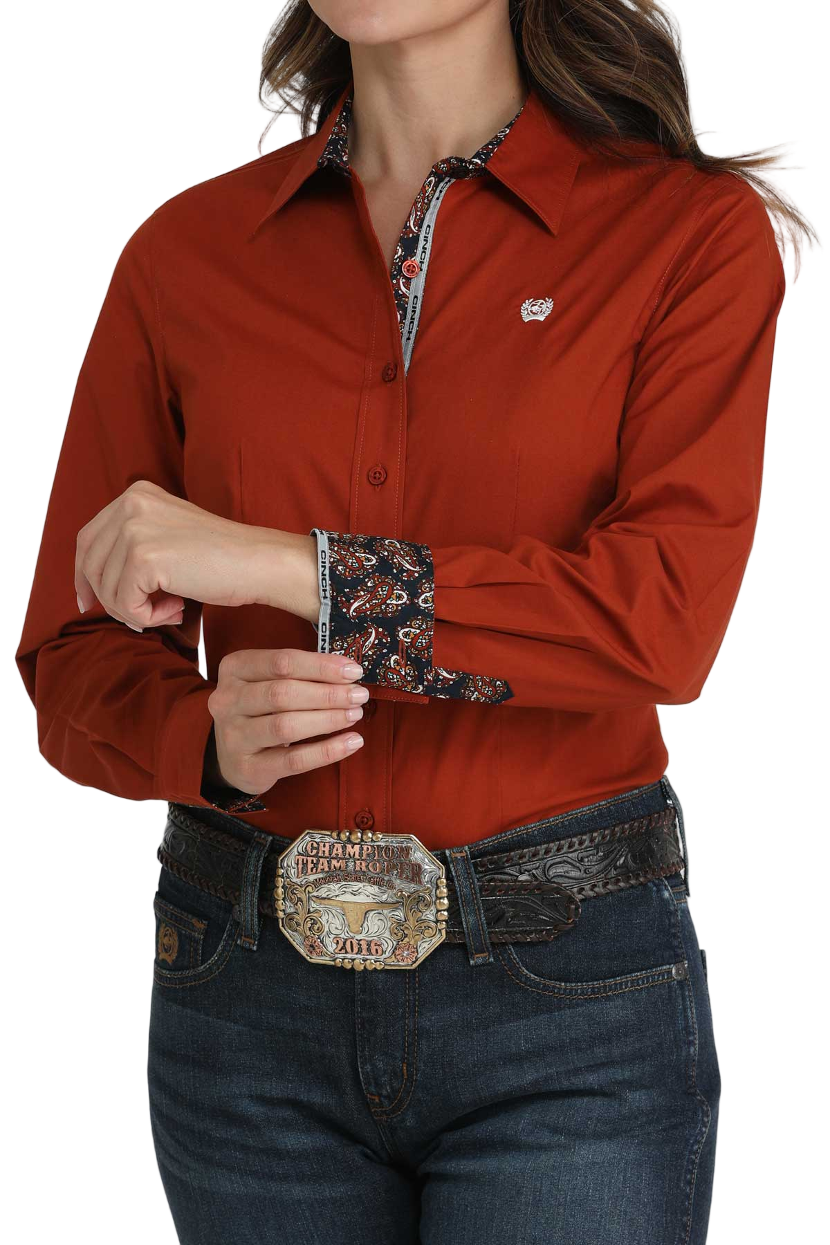 Woman wearing a red long-sleeve button-down shirt with contrasting cuffs, paired with jeans and a large western belt buckle