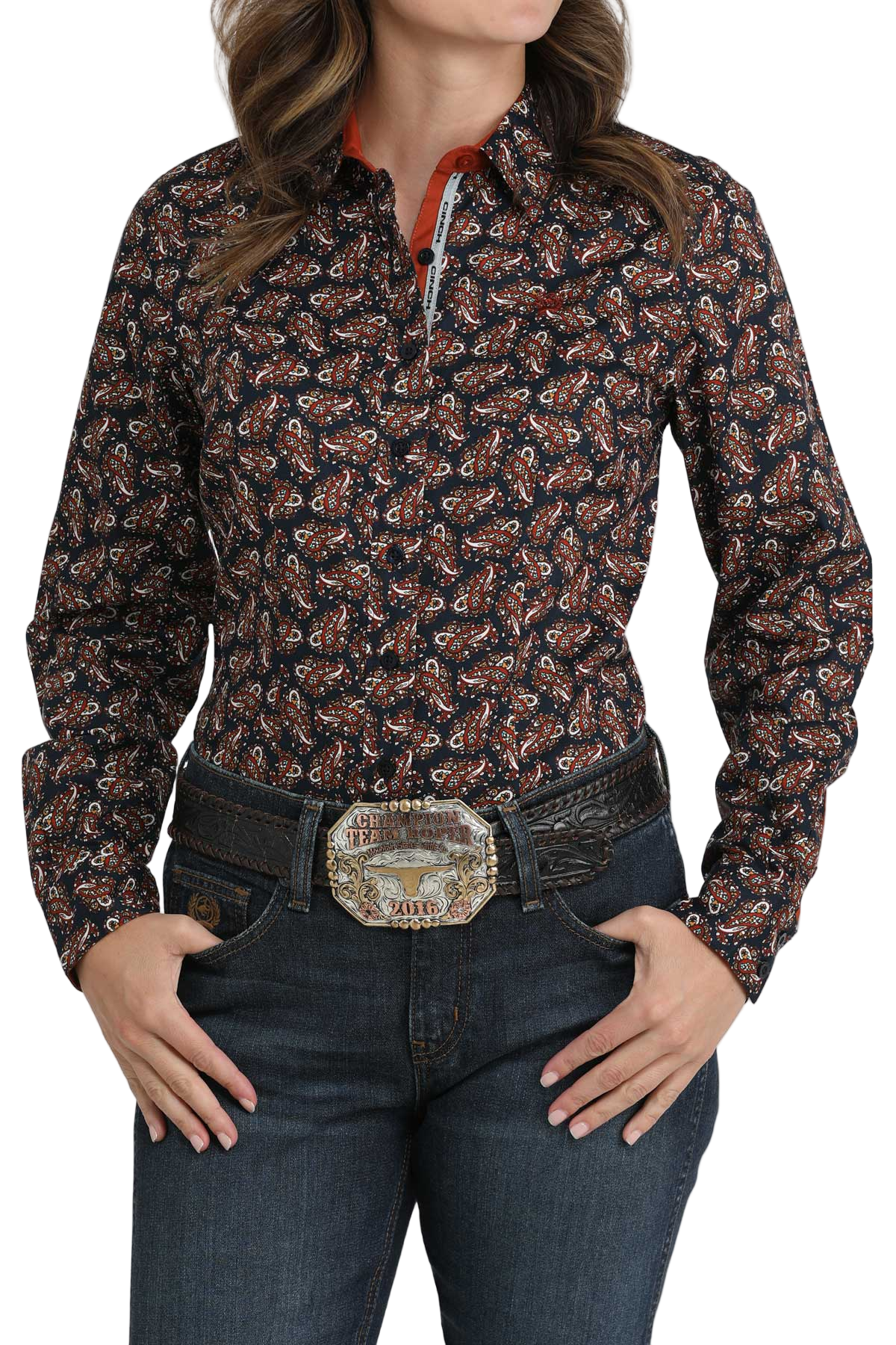 Woman wearing a dark patterned button-down shirt, paired with a tooled belt and dark denim jeans