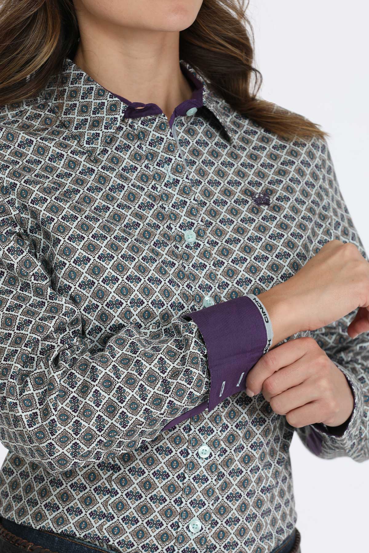 Close-up of a woman wearing a gray patterned button-up, showing off the shirt's purple contrasting cuffs