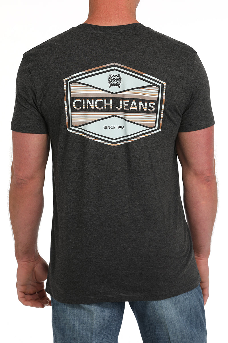Back view of a man wearing a dark gray t-shirt with a large 'Cinch' logo on it and blue jeans on a white background
