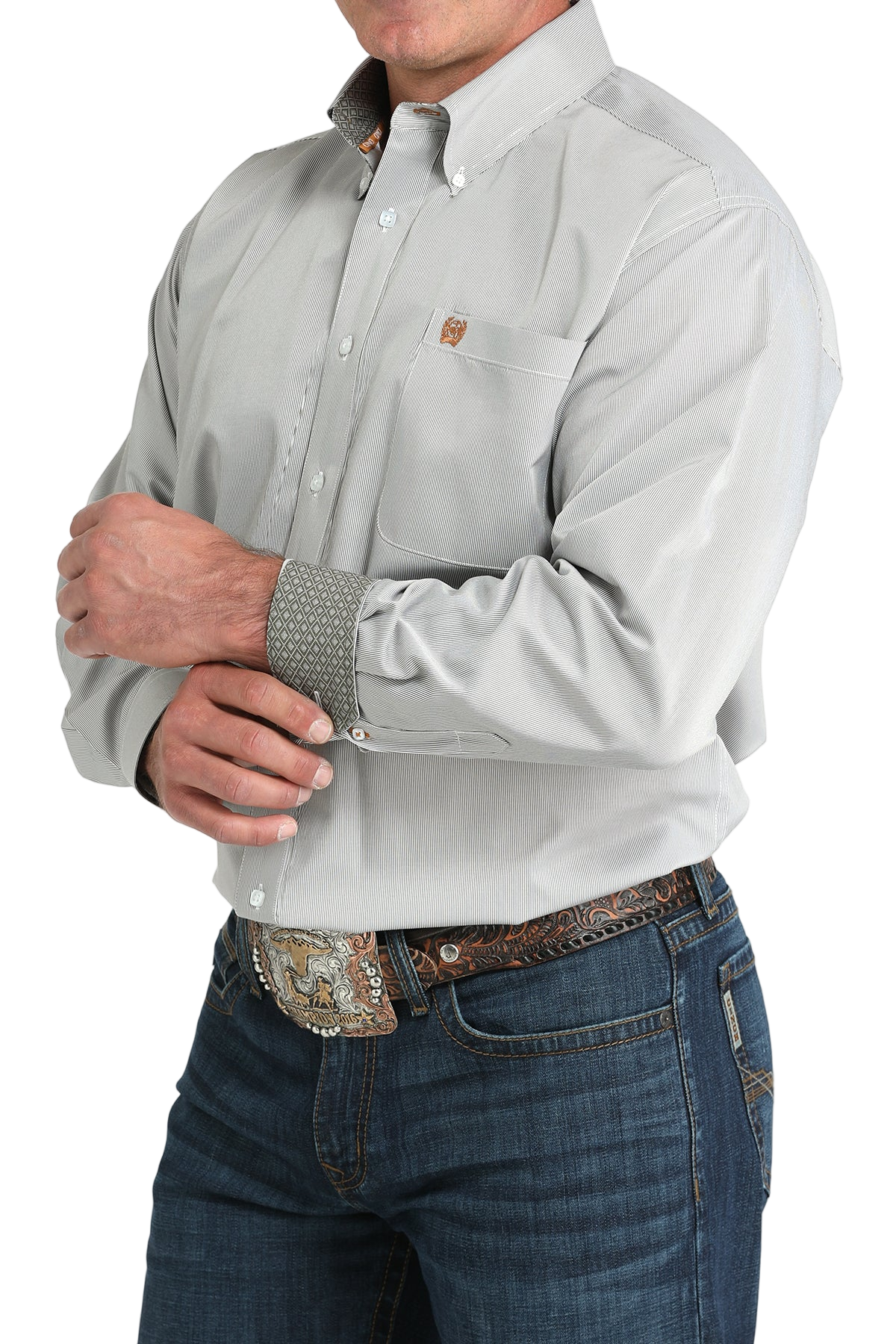 Man wearing a light gray button-up shirt with contrasting cuffs and blue jeans on a white background