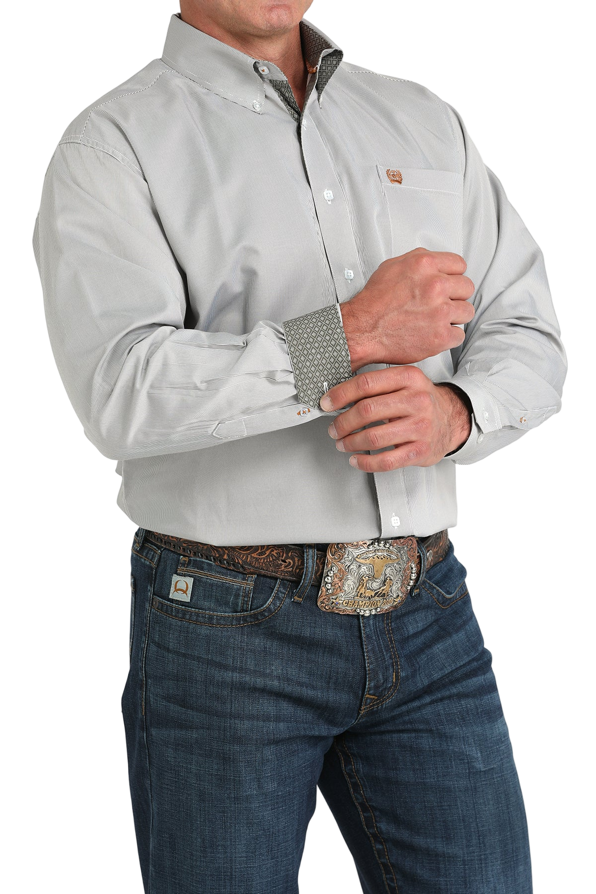 Man wearing a light gray button-up shirt with contrasting cuffs and blue jeans on a white background
