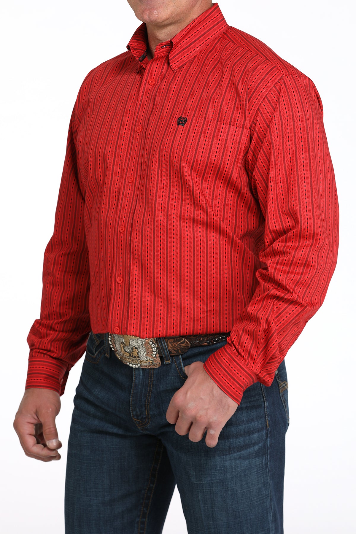 A man wearing a red striped button-up shirt, dark jeans, and a large belt buckle, standing against a white background