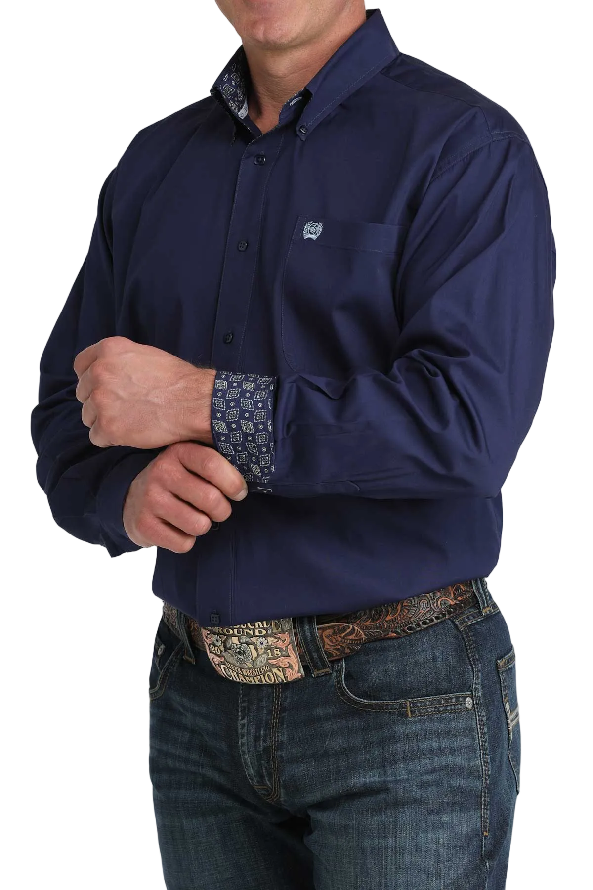Person wearing a navy blue shirt with a patterned cuff and jeans on a white background