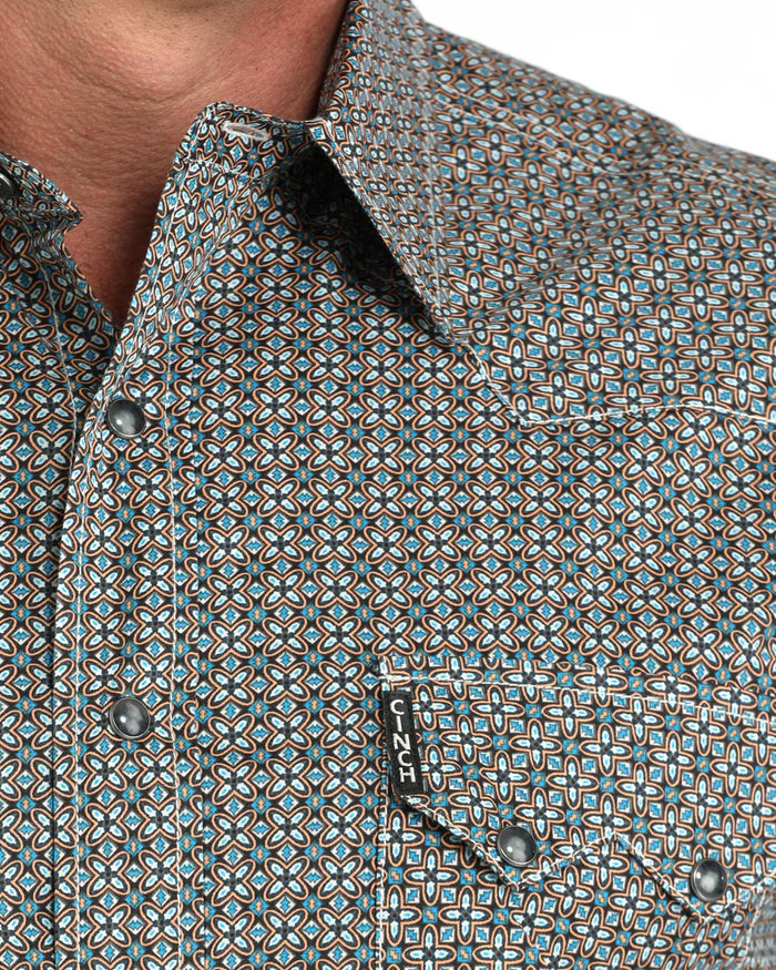 Close-up of a patterned shirt with a brand logo on a white background