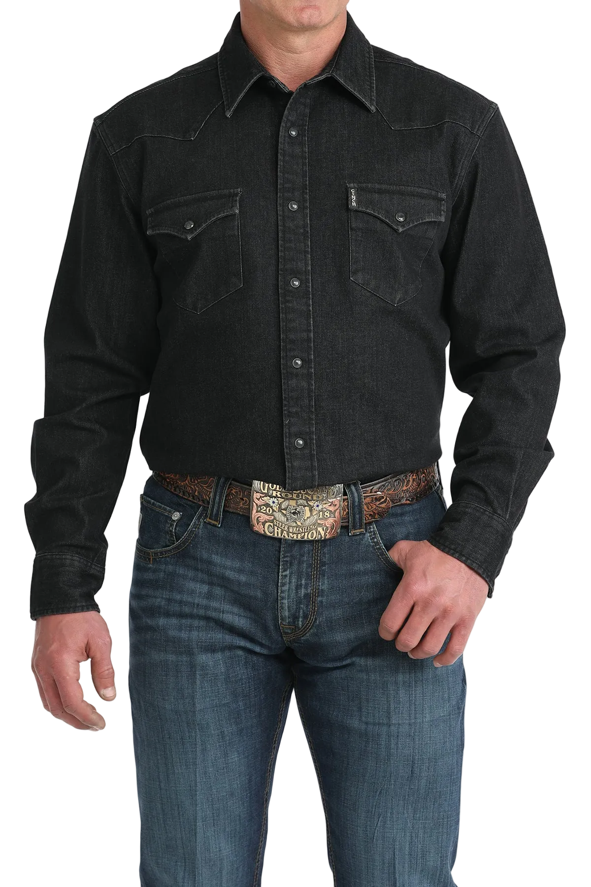 Man wearing a black denim shirt and blue jeans with a patterned belt on a white background