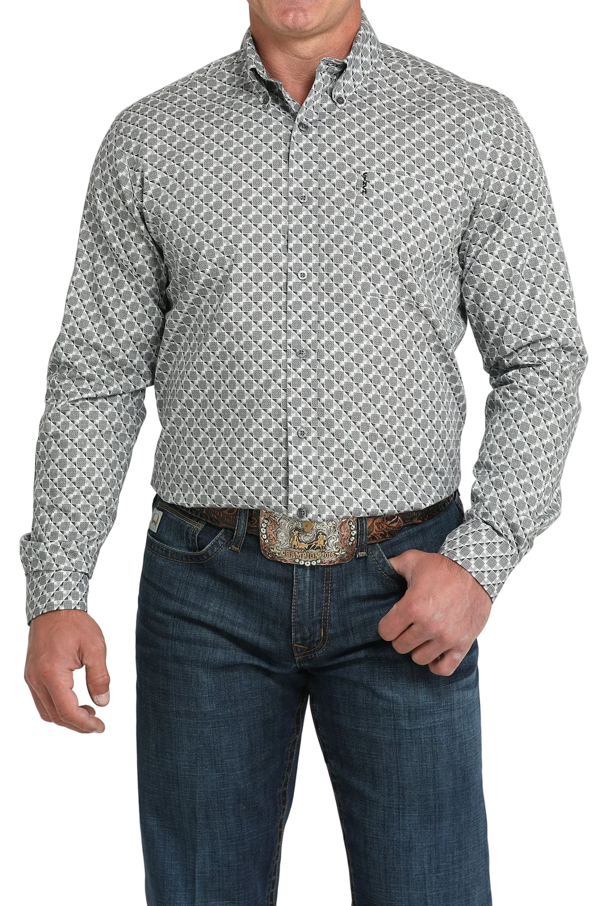 A man wearing a light gray patterned button-up shirt, dark jeans, and a large belt buckle, standing against a white background