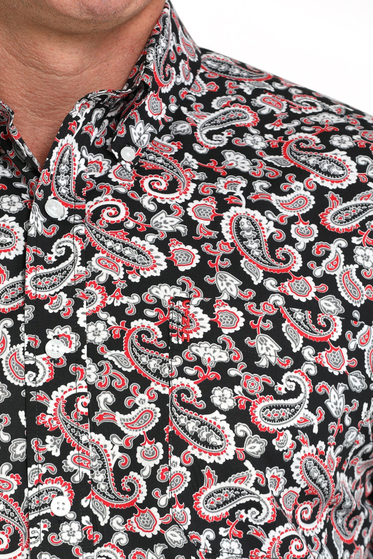 Close-up of a man wearing a black and red patterned button-up shirt with a chest pocket, displayed against a white background