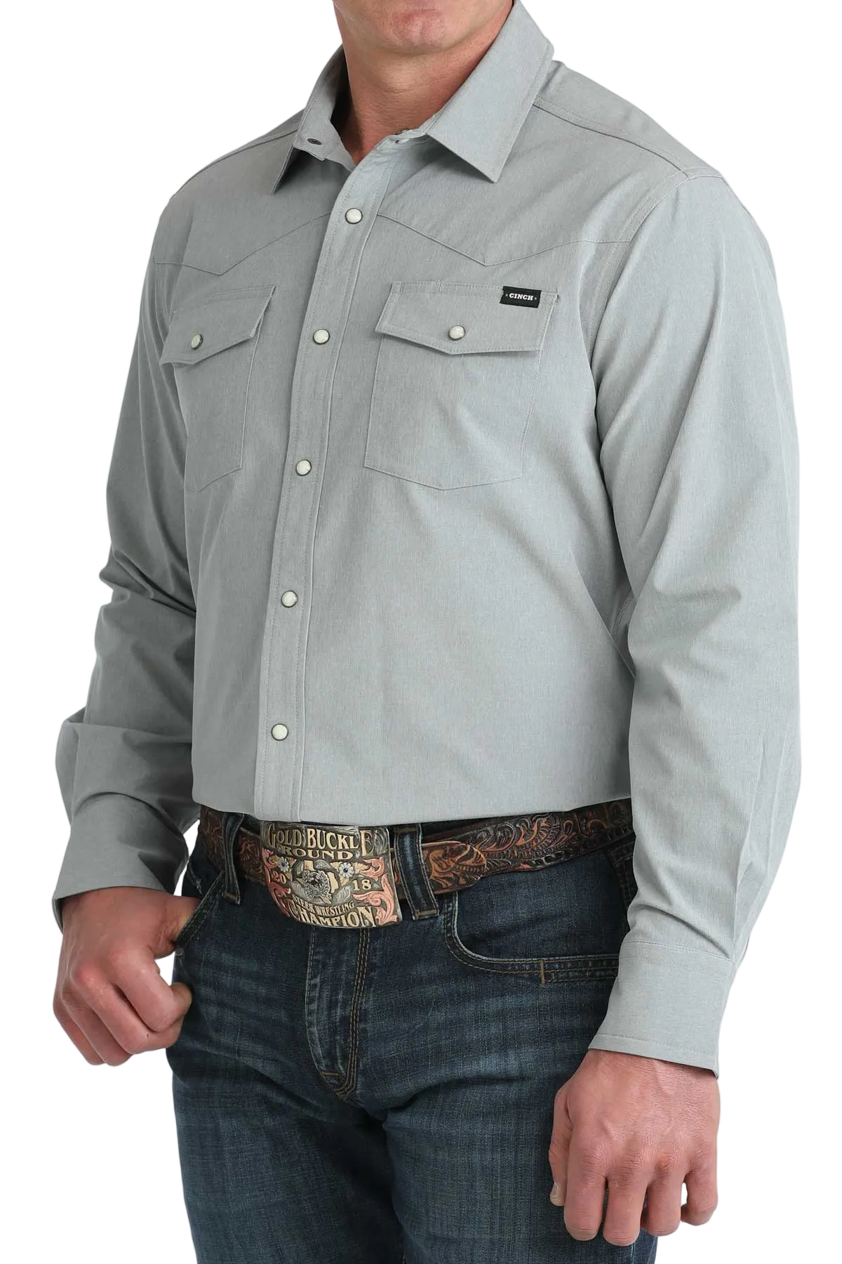 Man wearing a light gray button-up shirt and jeans on a white background