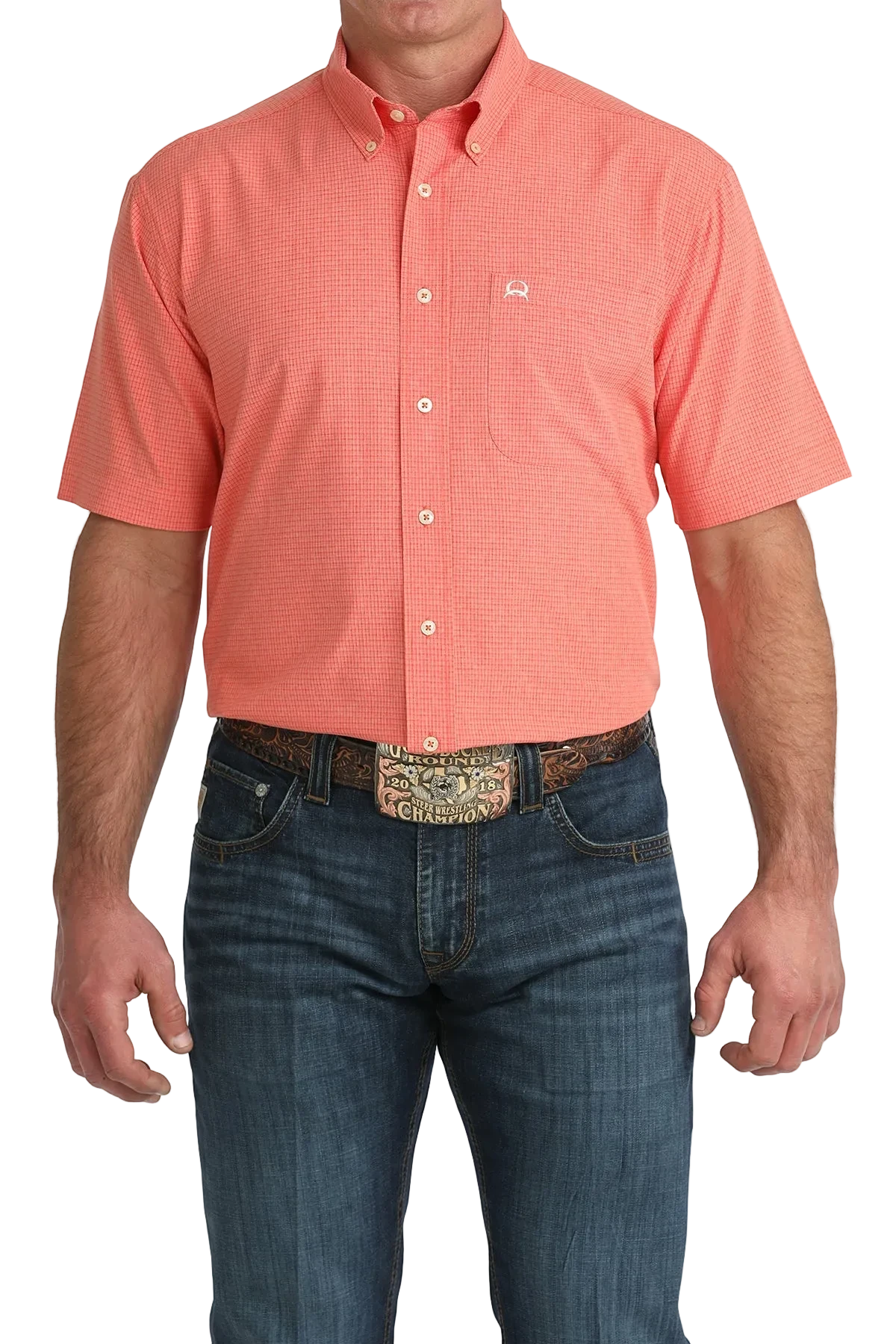 Man wearing a coral short-sleeve shirt and blue jeans with a patterned belt.