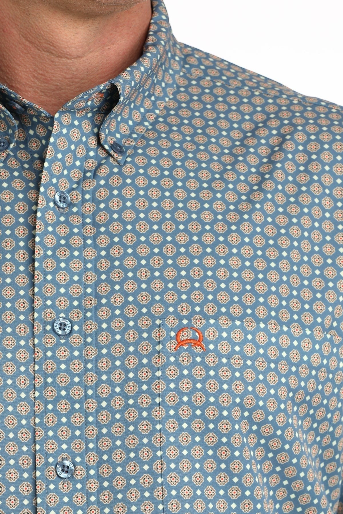 Go West Supply men's blue long sleeve button-down shirt with all-over geometric print and orange logo on chest pocket.