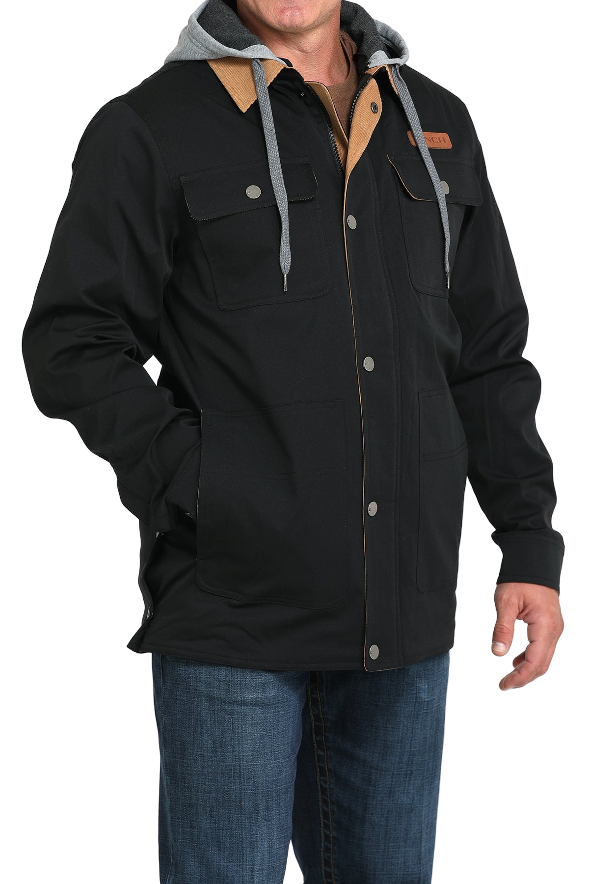 Man wearing a black jacket with a tan collar and attached gray hood, paired with blue jeans