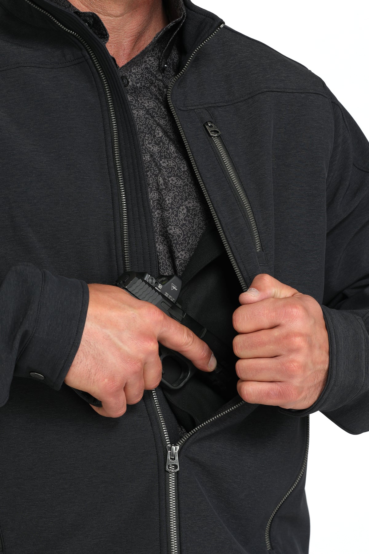 Close-up of a man wearing a black jacket showing a partial firearm going into the concealed carry pocket 