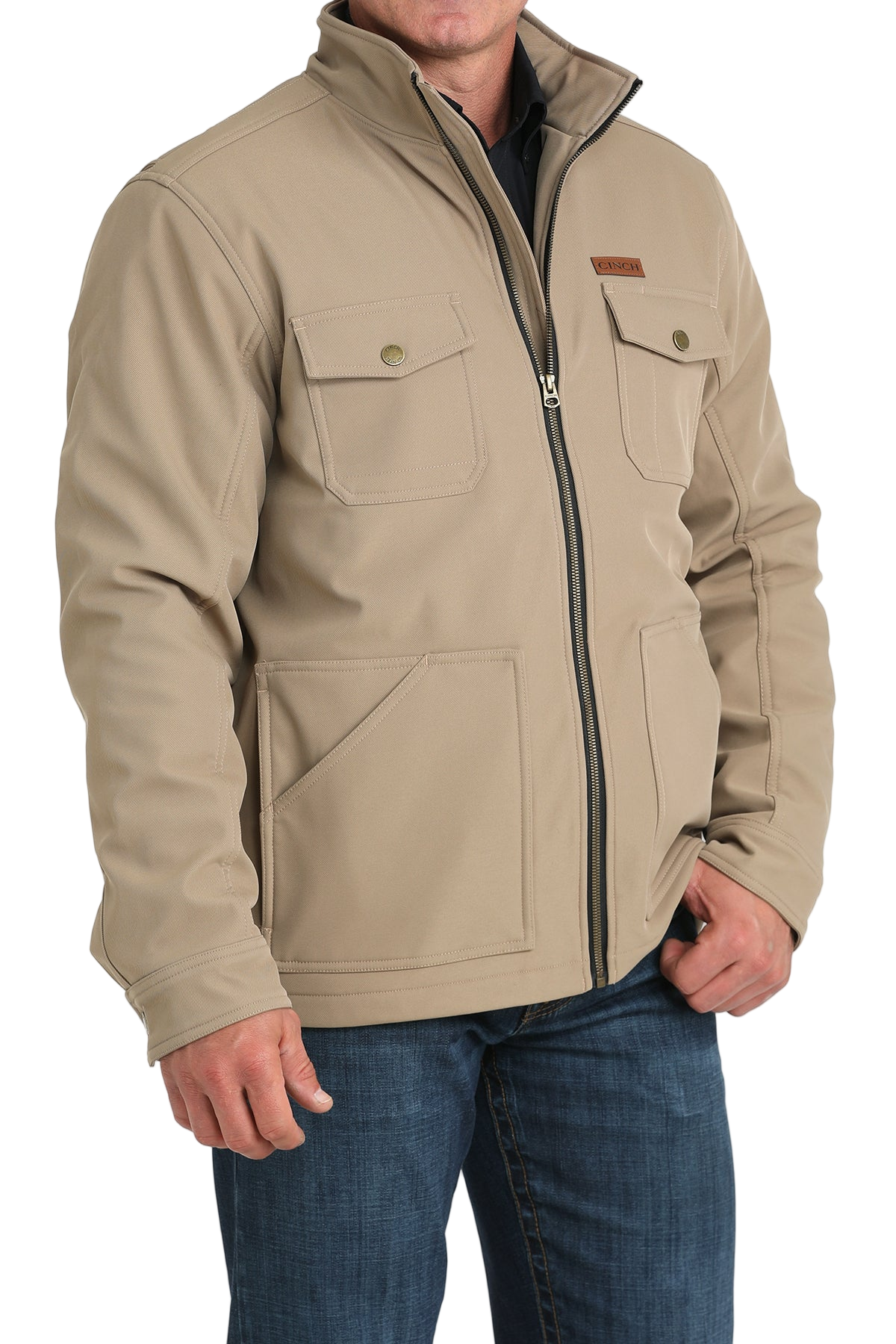 Man wearing a tan zip-front jacket with buttoned chest pockets, paired with dark jeans