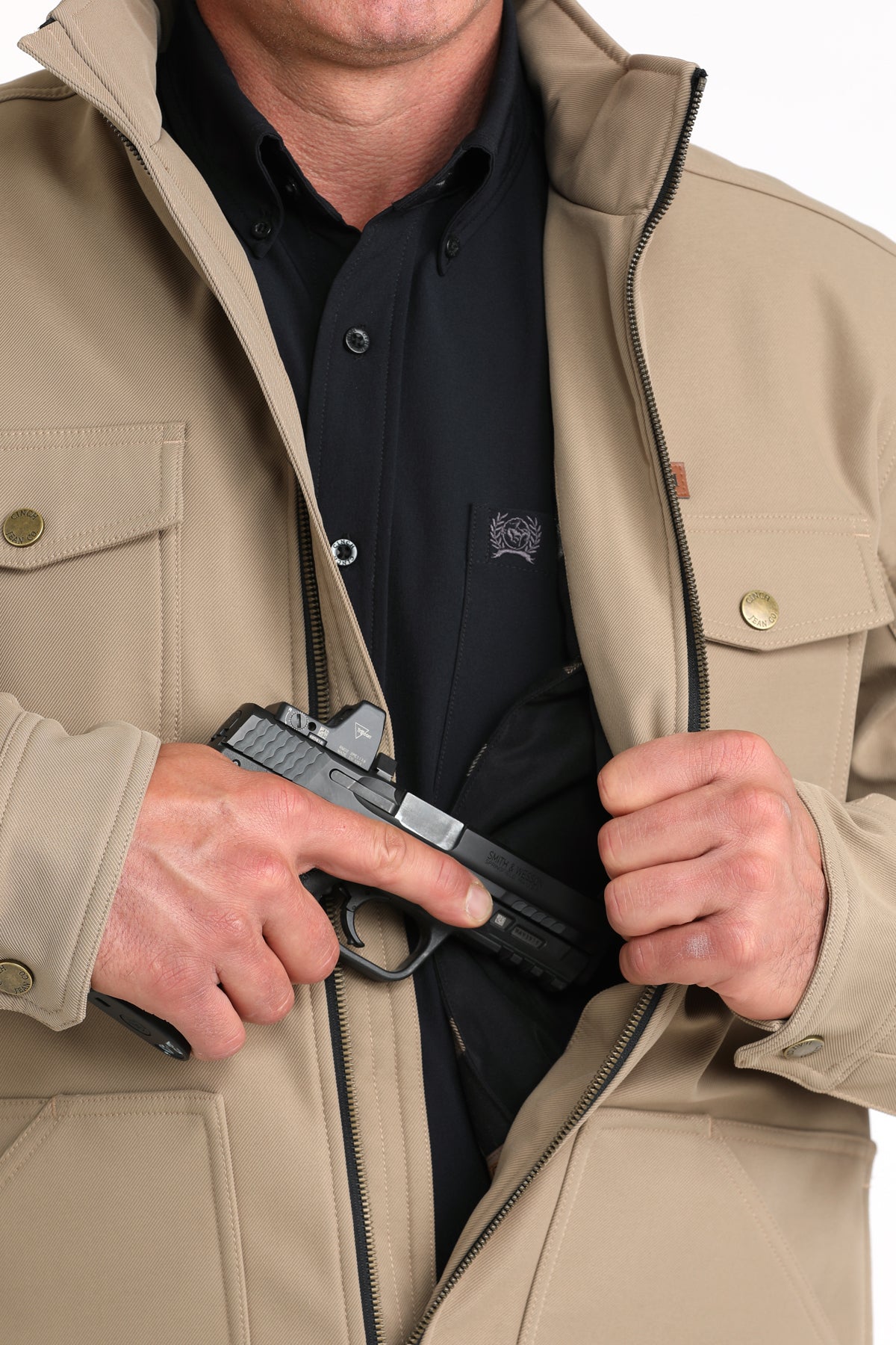 Close-up of a man wearing a khaki jacket showing a partial firearm going into the concealed carry pocket 
