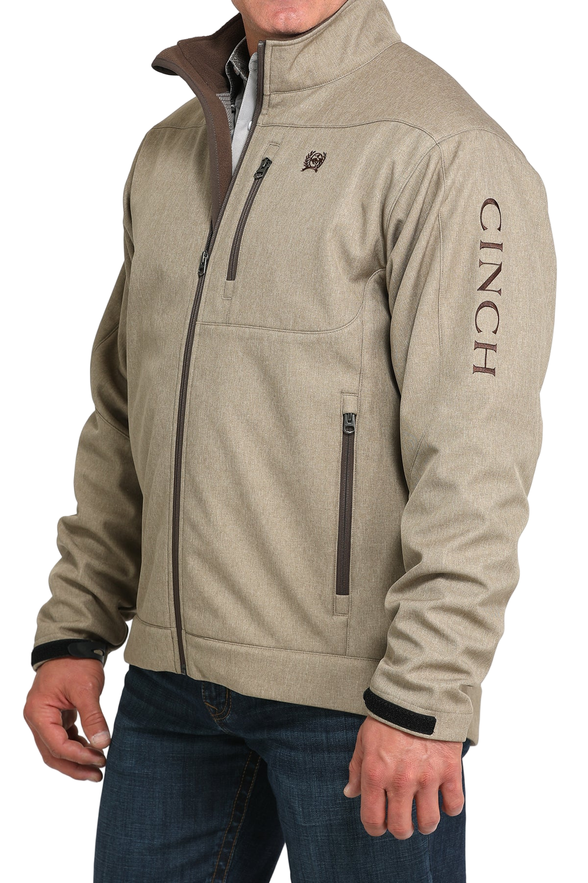 Man wearing a tan zip-front jacket, paired with dark jeans