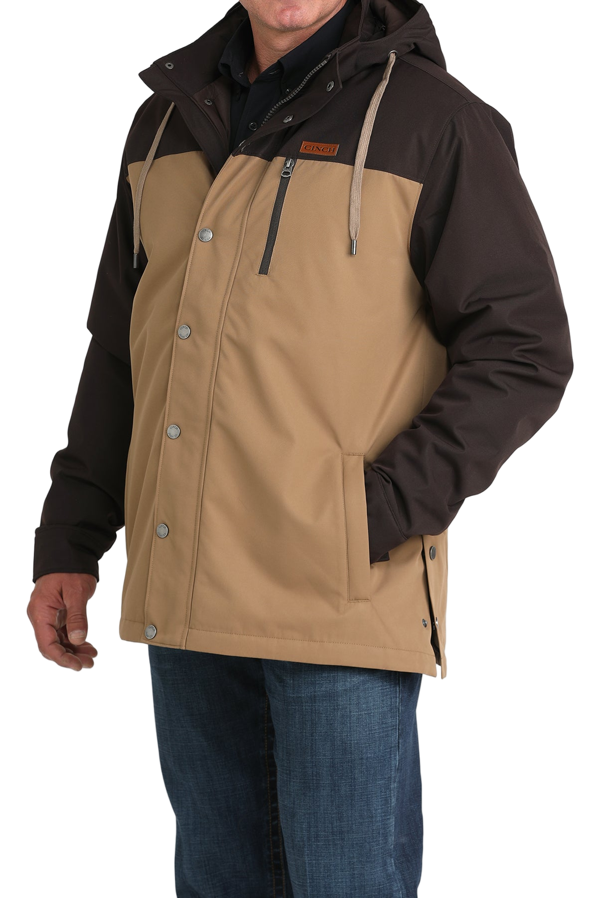 Man wearing a two-tone brown hooded jacket paired with blue jeans