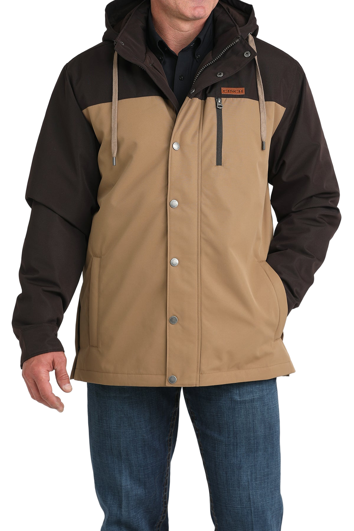 Man wearing a two-tone brown hooded jacket paired with blue jeans