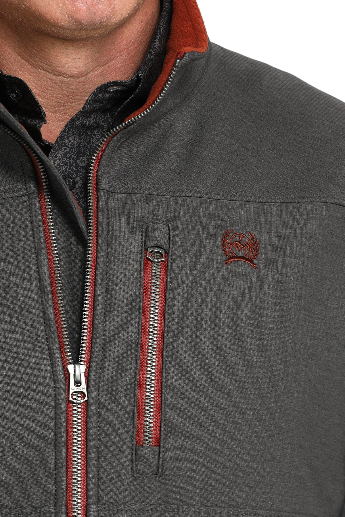 Close-up of a man wearing a charcoal gray softshell jacket with bold red accents