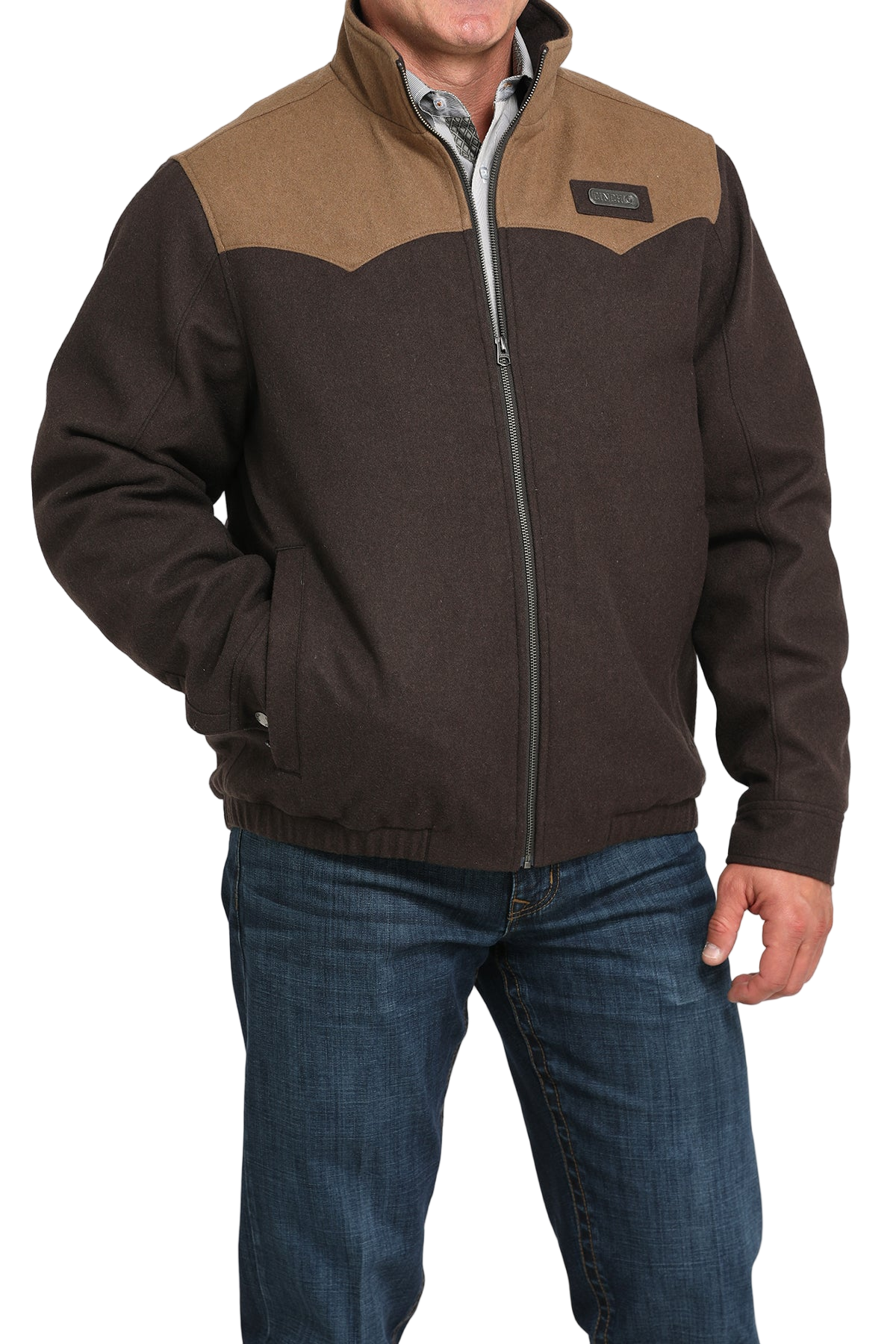 Man wearing a brown zip-up jacket with a lighter brown yoke detail, paired with blue jeans