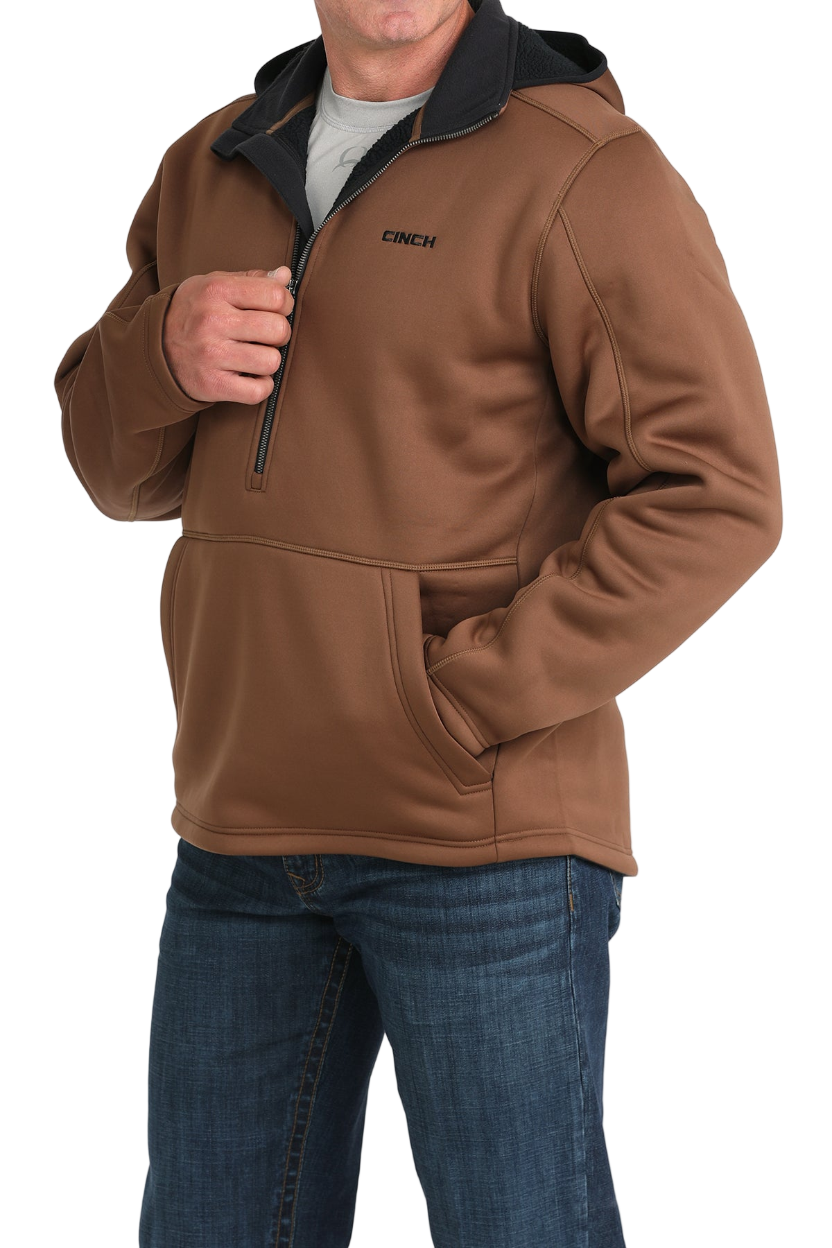 Man wearing a brown quarter-zip pullover with a black inner collar and a front kangaroo pocket, paired with blue jeans