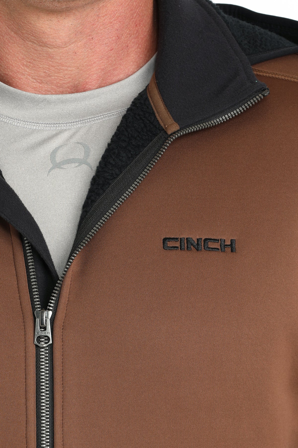 Close-up of a man wearing a brown sherpa hoodie with a zipper and small 'CINCH' logo